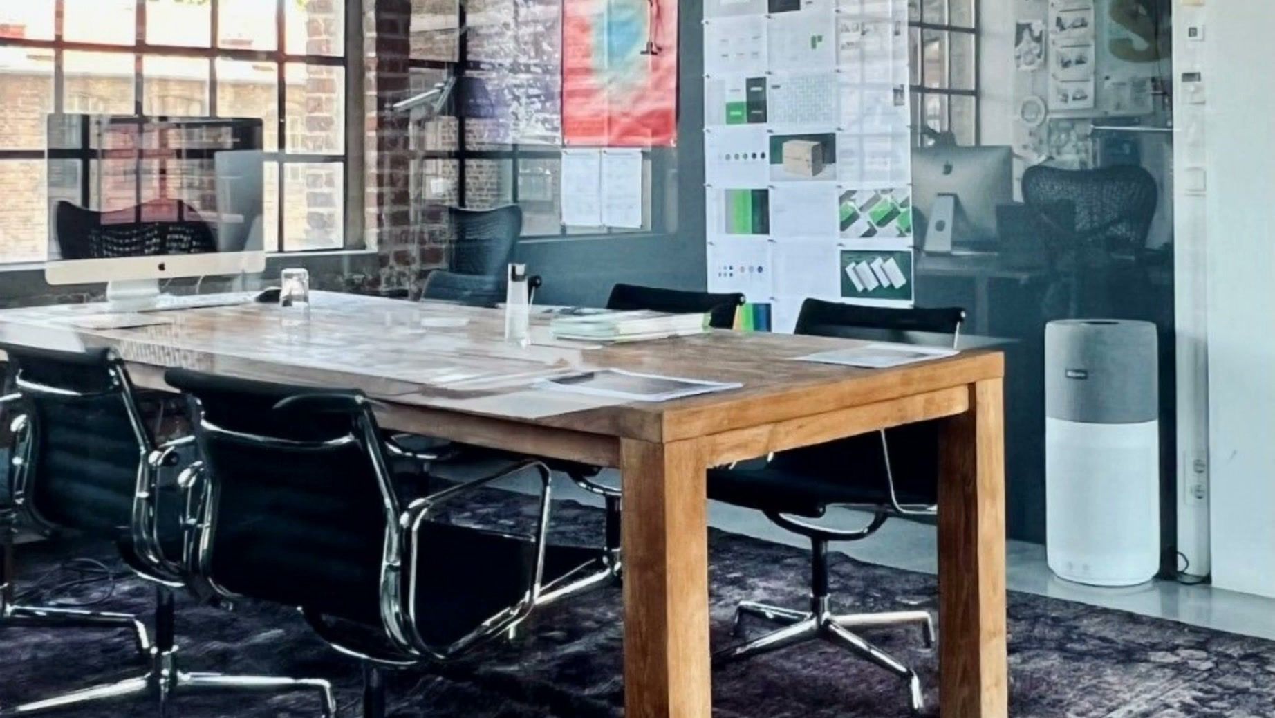 Meeting room with a long wooden table, black office chairs and industrial windows