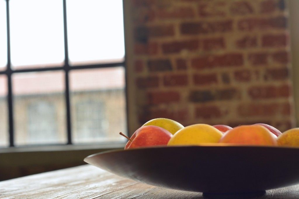 Fruit bowl with apples on a wooden table by the window