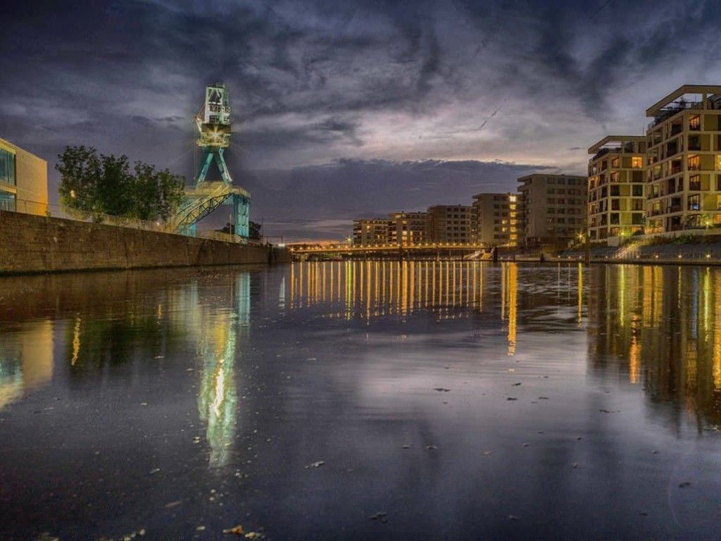 Offenbach harbour in the evening, a lit crane and flats reflected in the water