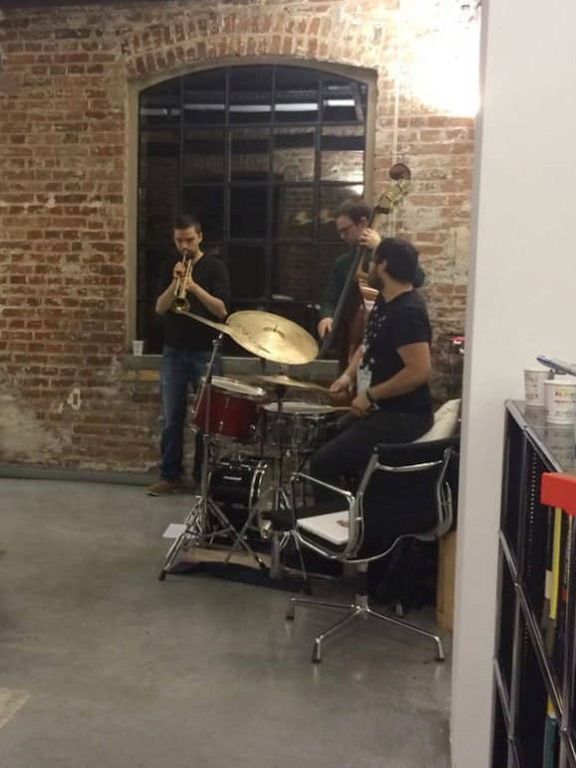 A jazz trio with trumpet, double bass and drums playing in the office