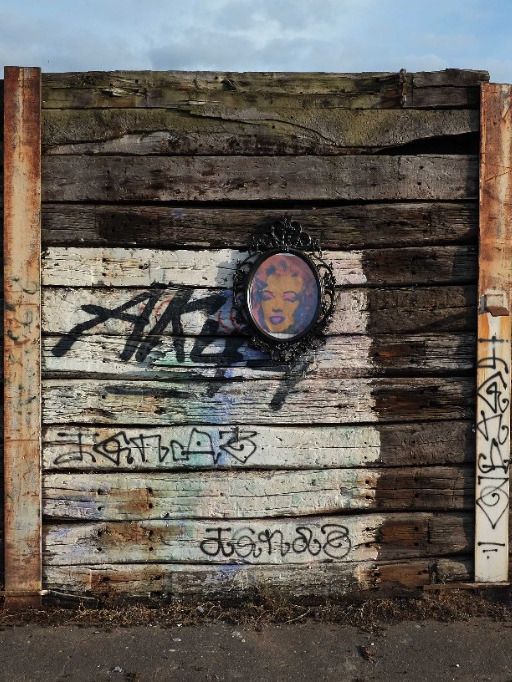 Wooden wall with graffiti and a framed portrait of Marilyn Monroe