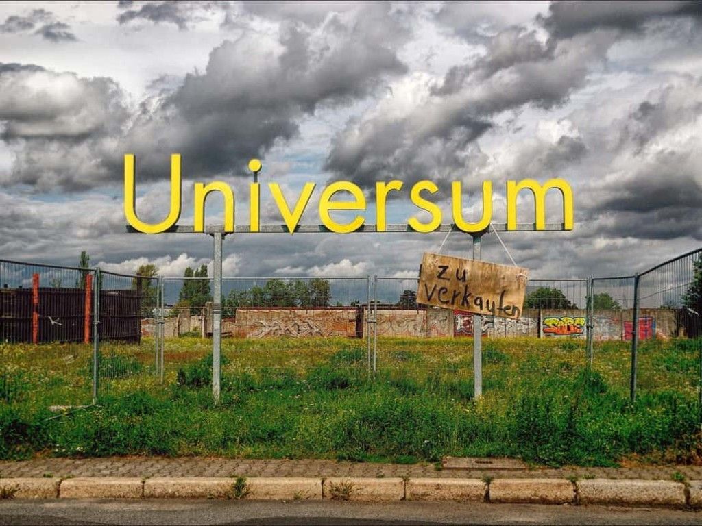 Yellow “Universum” lettering with a “zu verkaufen” (for sale) sign on a vacant lot