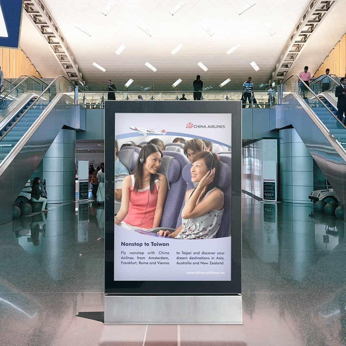 City light poster in a hall with escalators: two passengers wearing headphones and the line “Nonstop to Taiwan”