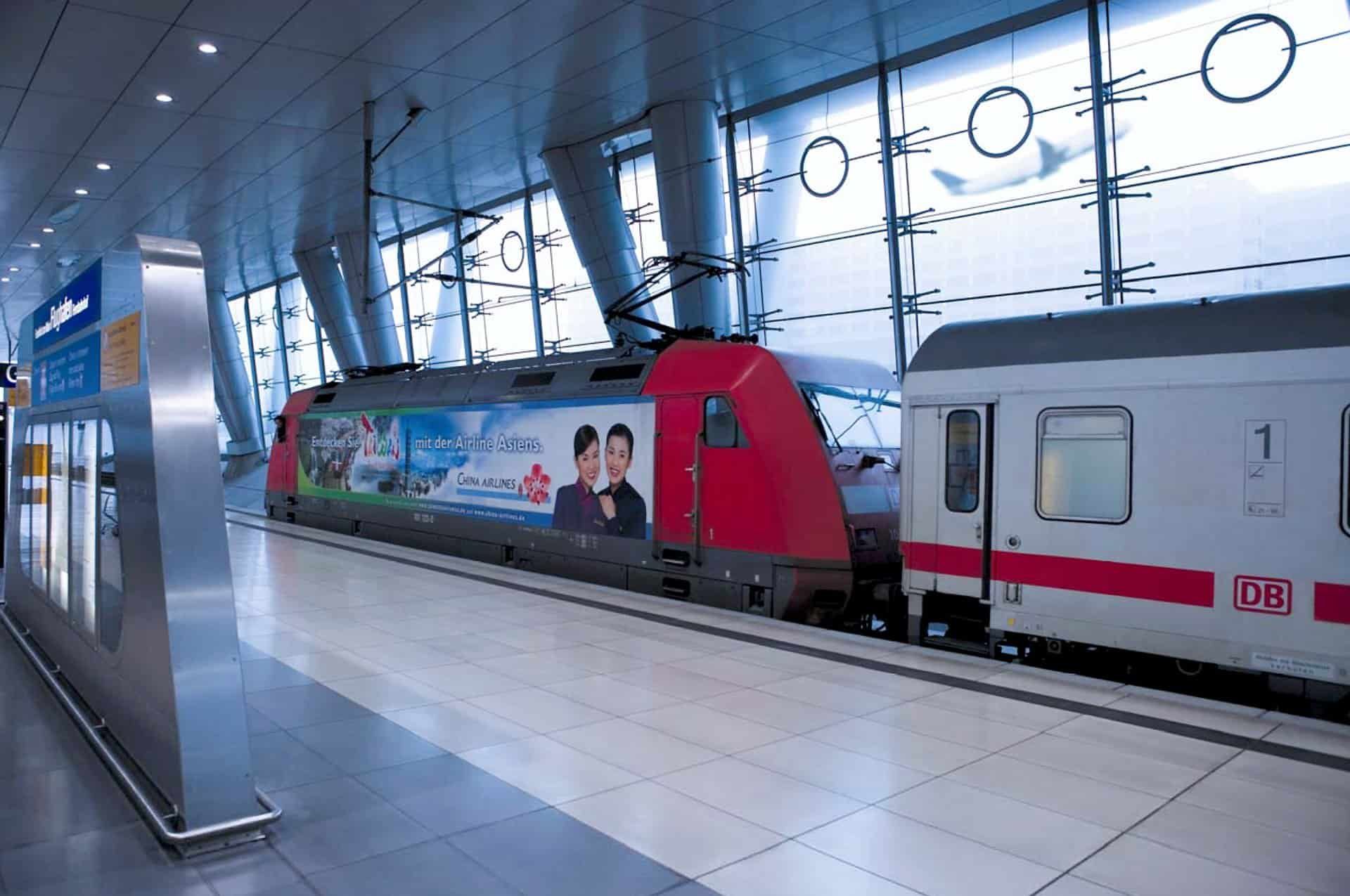 Locomotive with China Airlines advertising at a platform under a glass facade, next to a Deutsche Bahn carriage