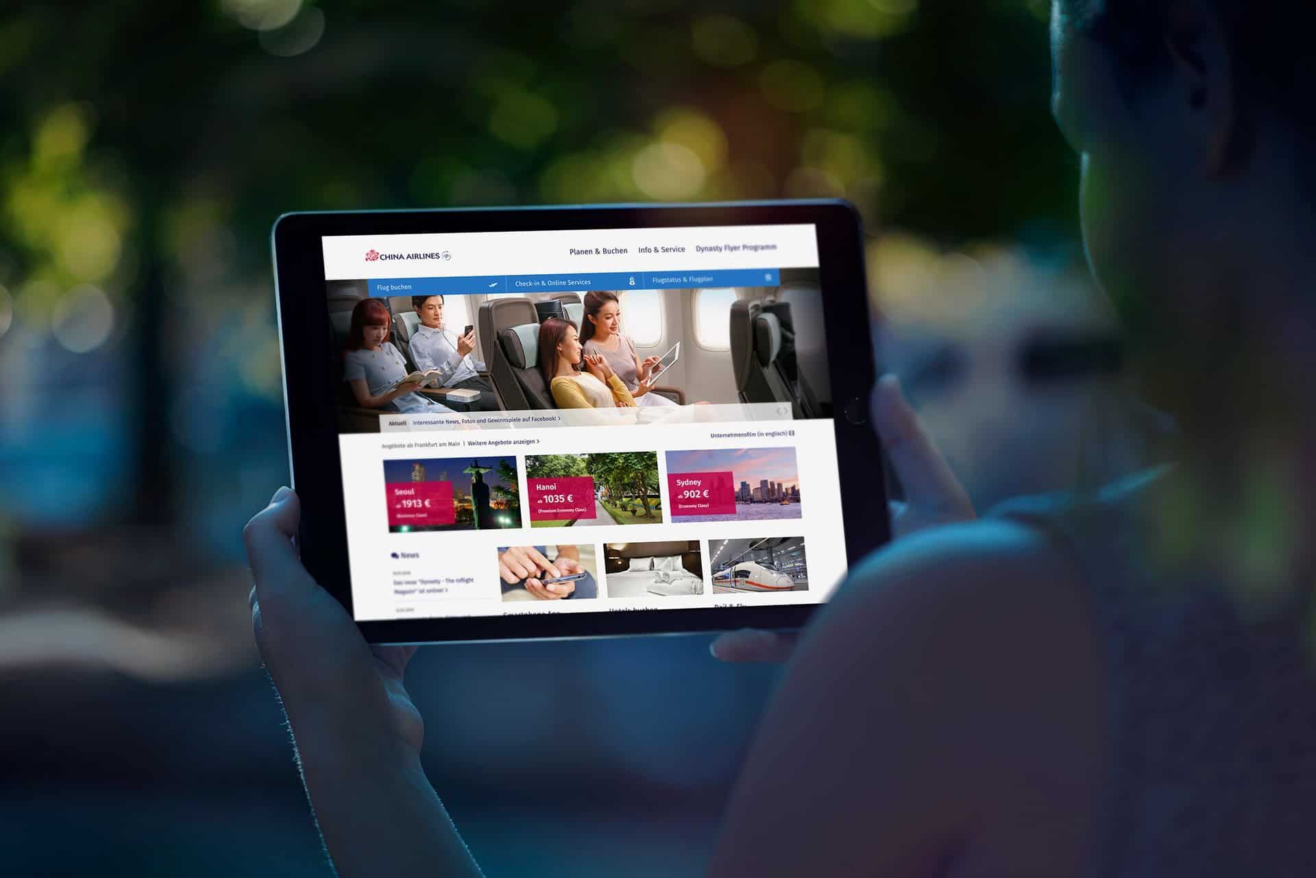 Hands holding a tablet with the German China Airlines website: flight offers from Frankfurt to Seoul, Hanoi and Sydney