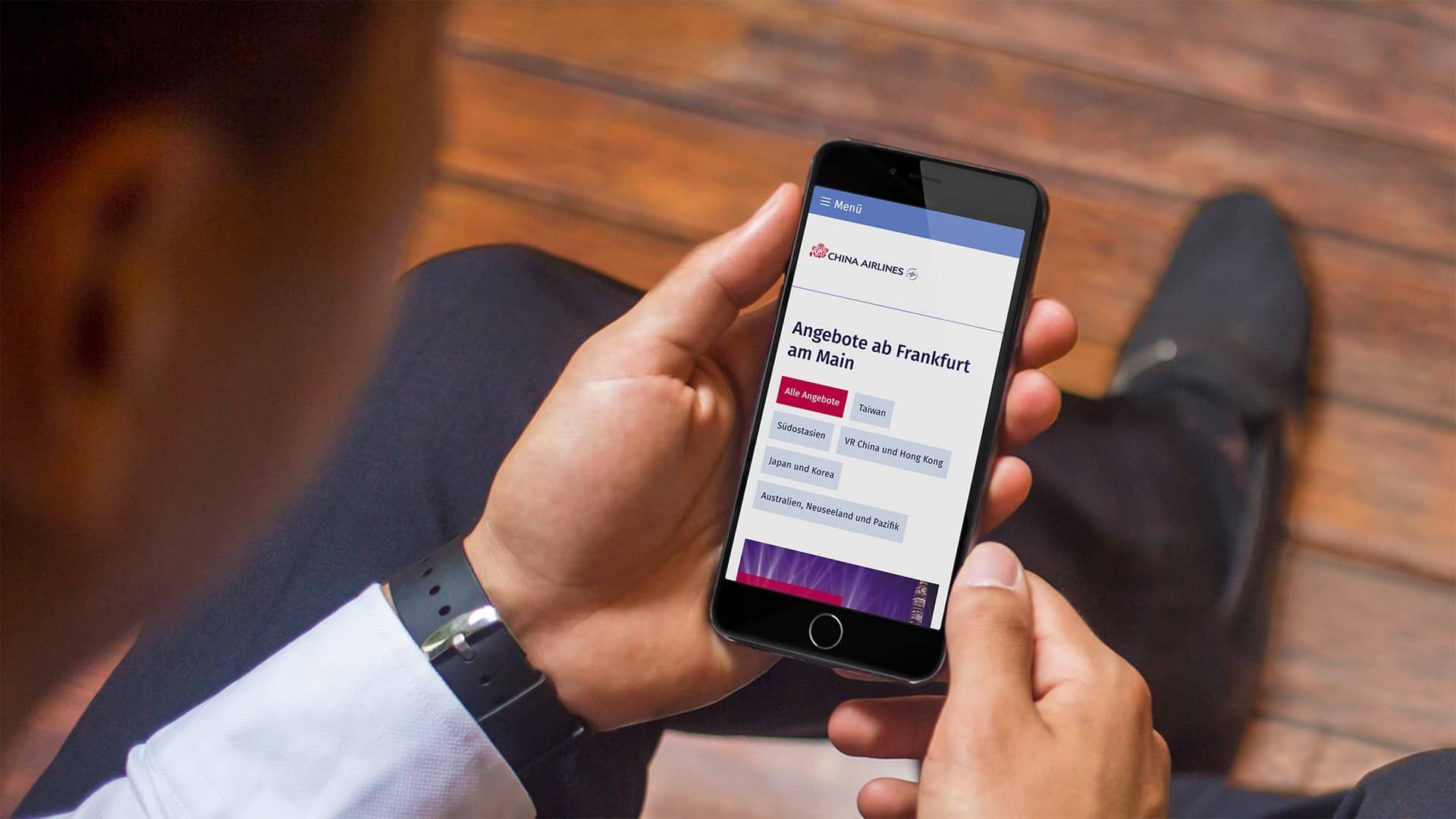 A man holding a smartphone with the mobile China Airlines website and its offers from Frankfurt am Main