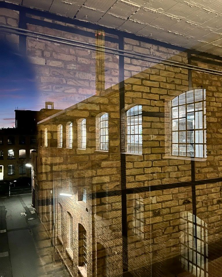 Brick façade at dusk, reflected in an office window