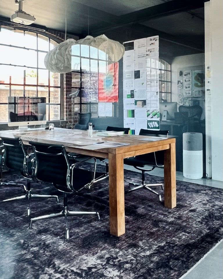 Meeting room with a wooden table, a paper lamp and design drafts on the wall