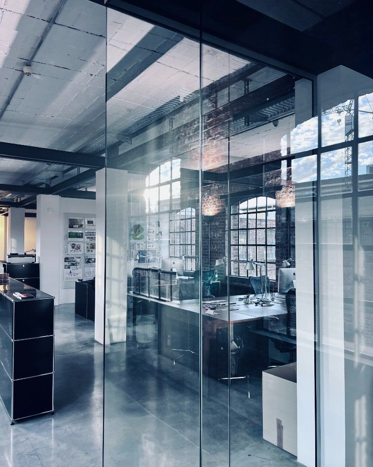 Office behind glass walls with desks in front of arched windows