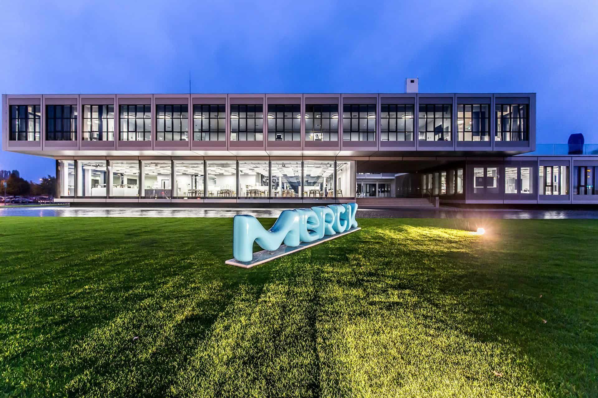 The Merck KGaA Innovation Center at dusk, with the Merck lettering on the lawn in front