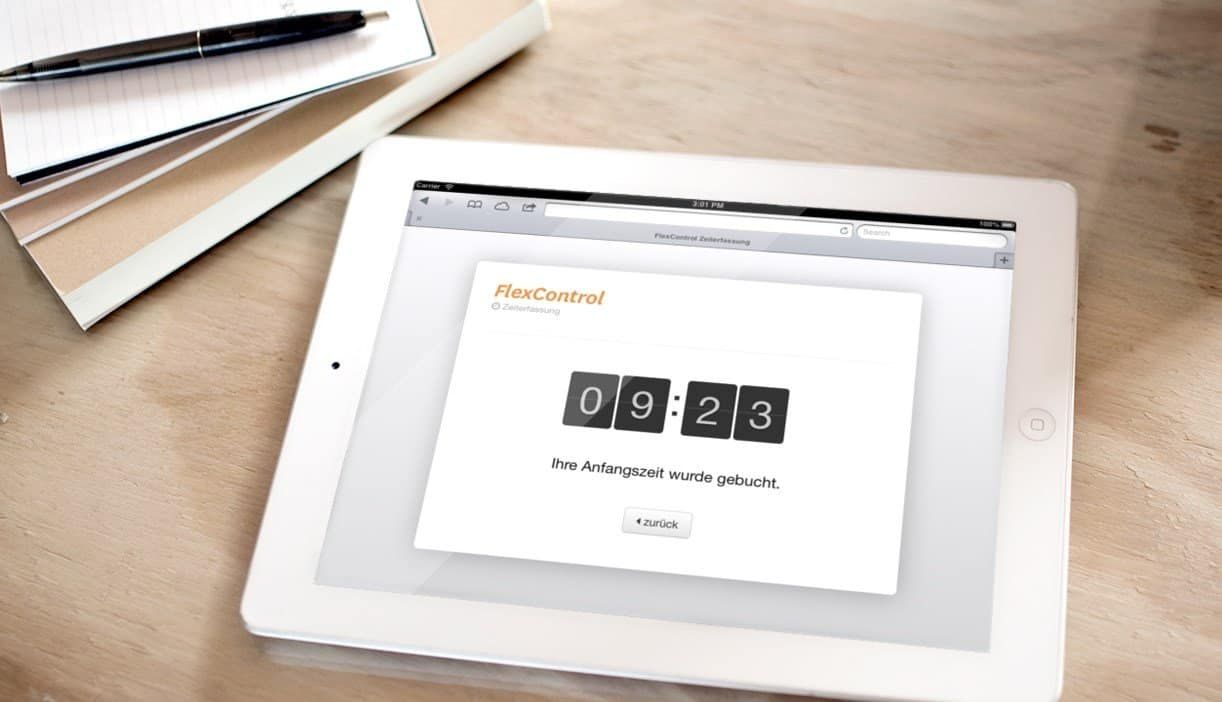 Tablet on a wooden table showing FlexControl time tracking: “Ihre Anfangszeit wurde gebucht.” (your start time has been booked)