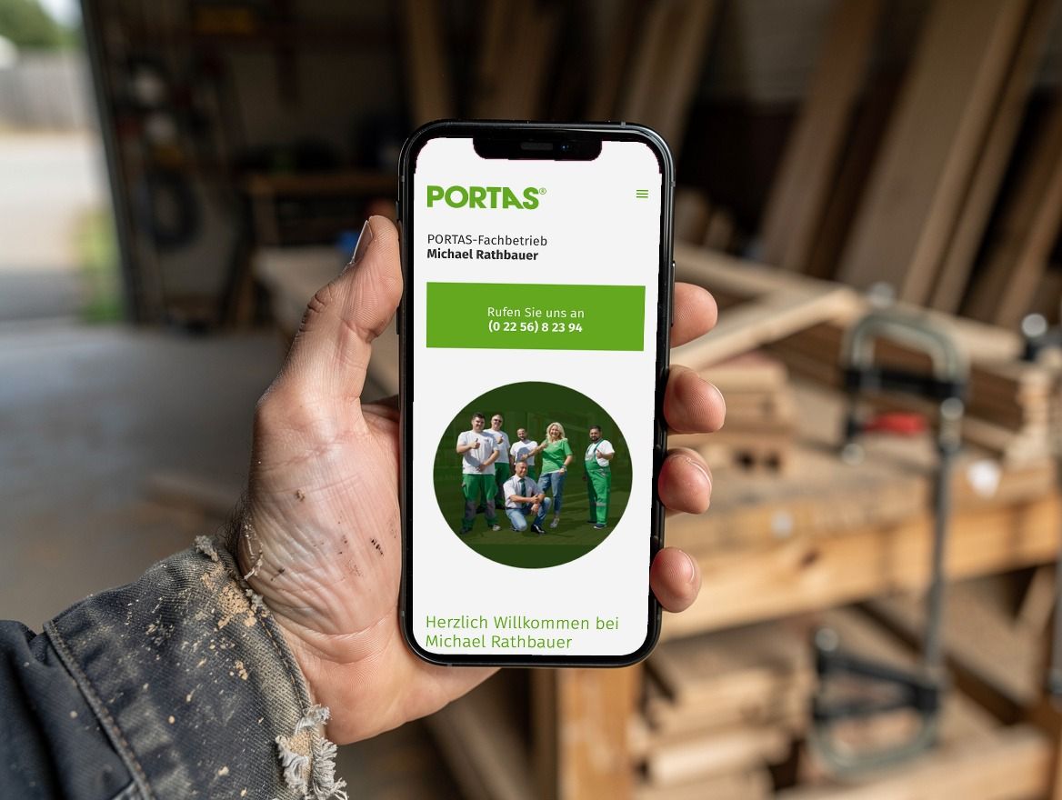 A craftsman’s hand holding a smartphone with the mobile website of an Austrian PORTAS franchise business