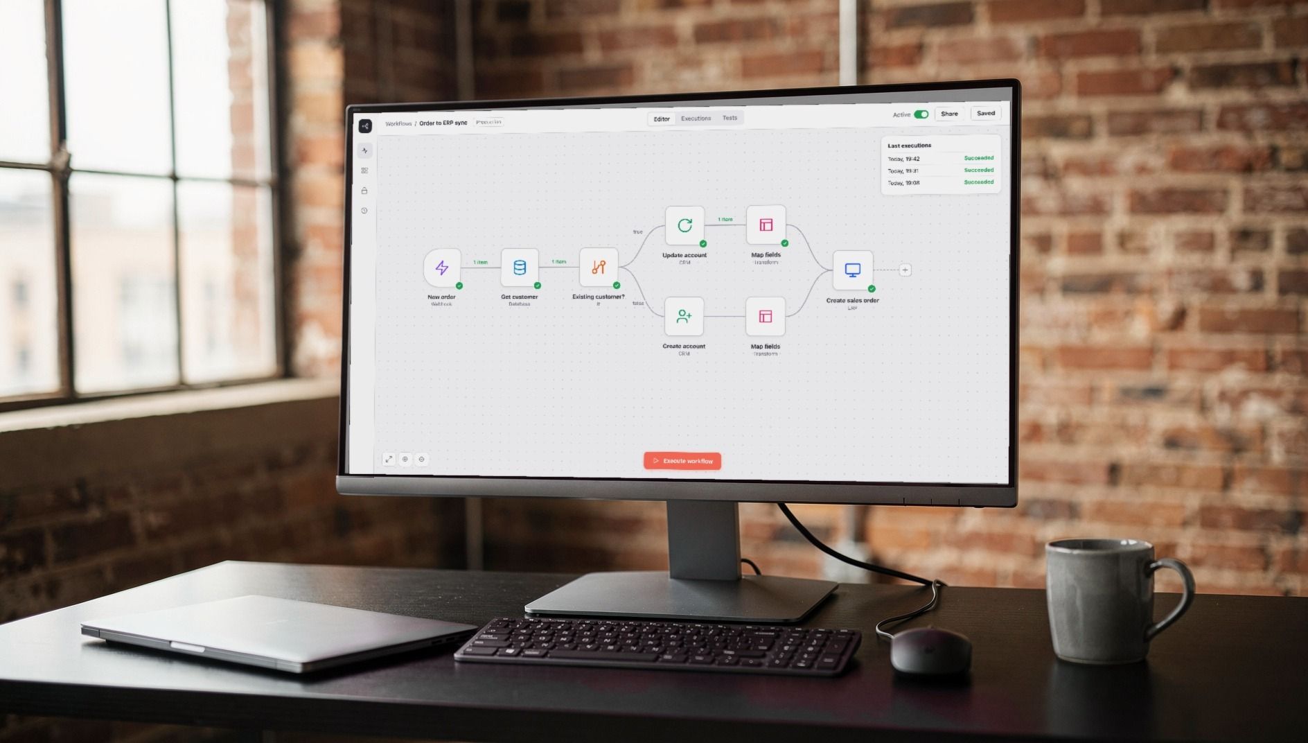 Monitor on a black desk showing a workflow that passes orders through a database and the CRM to the ERP automatically, a brick-walled loft behind it